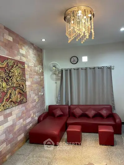 Stylish living room with red sofa, elegant chandelier, and decorative wall art.