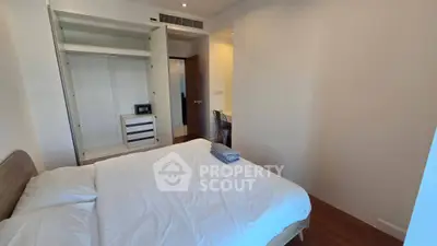 Cozy bedroom with open closet and wooden flooring, perfect for relaxation.