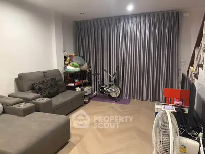Cozy living room with modern gray sofa and exercise bike, perfect for relaxation and fitness.