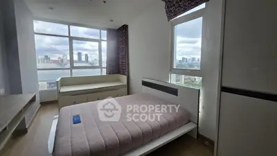 Modern bedroom with large windows and city view, featuring stylish furniture and ample natural light.