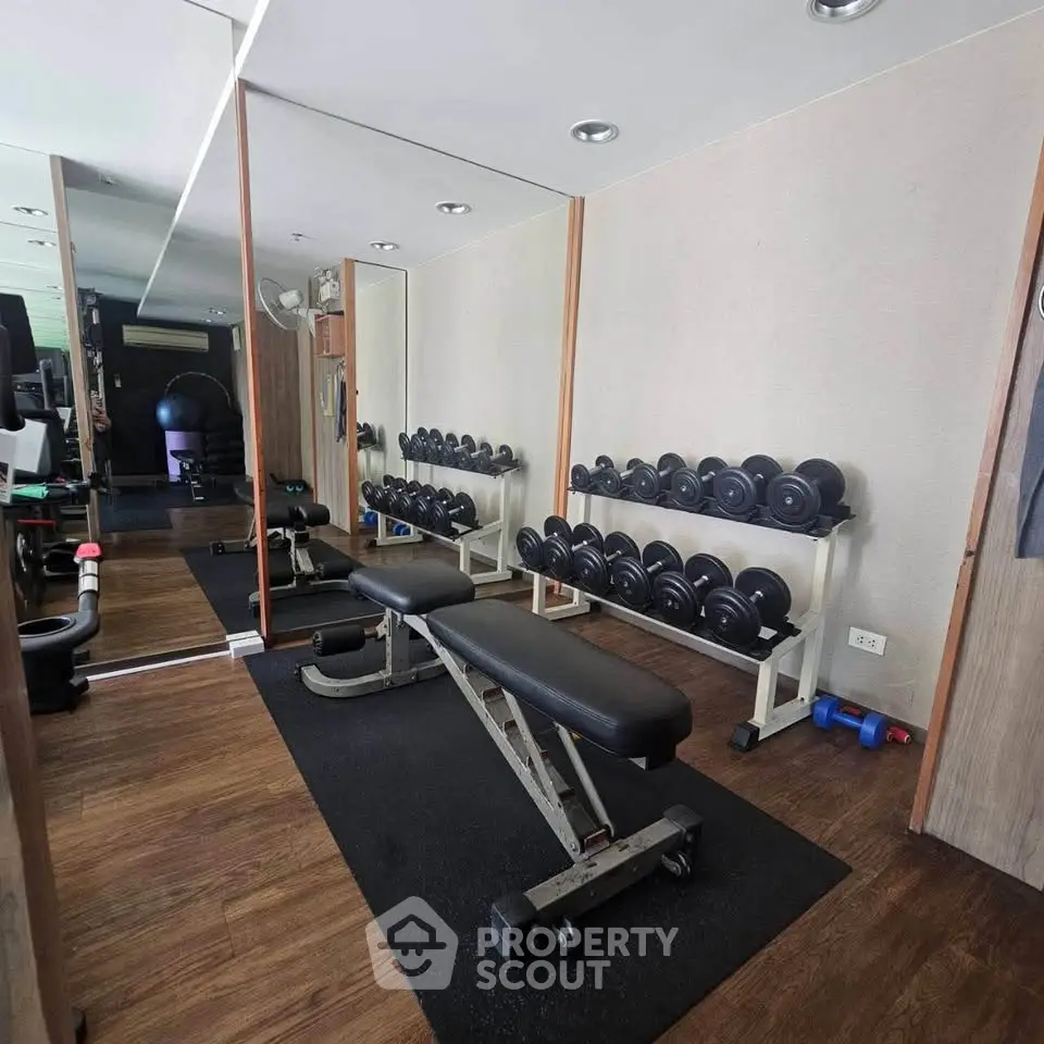 Modern gym with free weights and benches in a sleek real estate property.