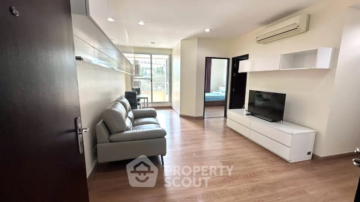 Modern living room with sleek furniture and open layout, featuring a cozy bedroom view.
