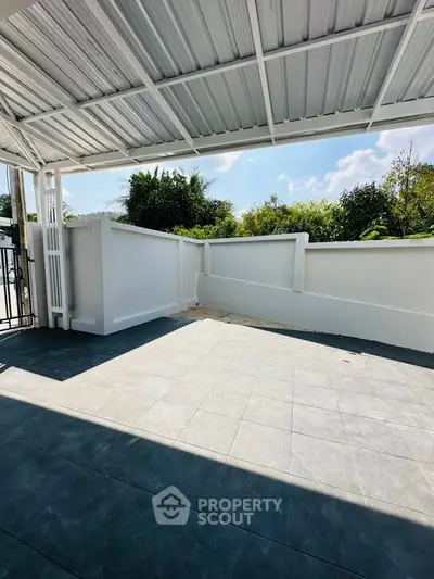 Spacious outdoor patio with tiled flooring and partial roof cover, perfect for relaxation and entertainment.