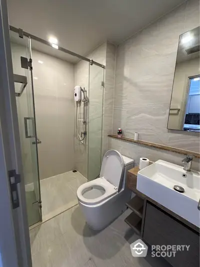 Modern bathroom with glass shower and sleek fixtures in contemporary apartment.