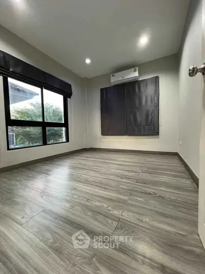 Spacious empty room with large windows and modern flooring, perfect for customization.