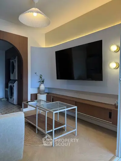 Modern living room with wall-mounted TV and stylish furniture, featuring a cozy ambiance and elegant lighting.
