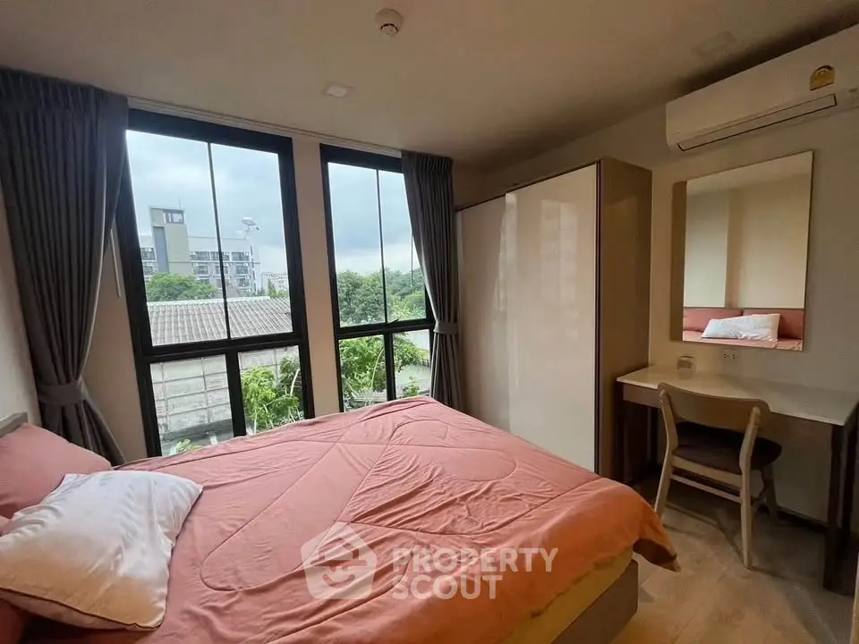 Cozy bedroom with large windows and modern furnishings, offering a serene view.