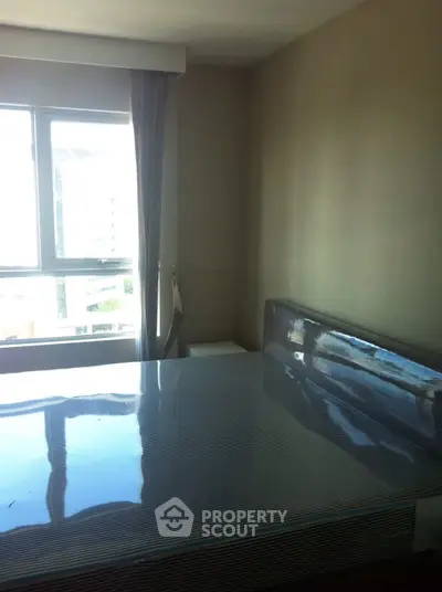 Spacious bedroom with large window offering natural light and city views, featuring a modern bed setup.