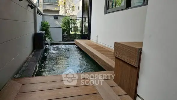 Modern outdoor pool area with sleek wooden deck and water feature.