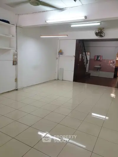 Spacious tiled room with staircase and sink, ideal for versatile use.