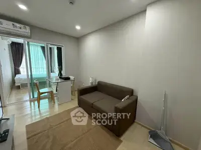 Modern living room with brown sofa and sliding glass doors leading to bedroom