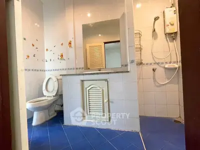 Spacious bathroom with modern shower and blue tile flooring in a cozy home.