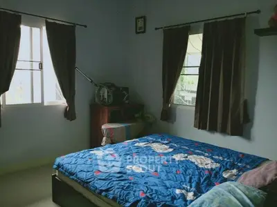 Cozy bedroom with blue bedding and natural light from two windows.