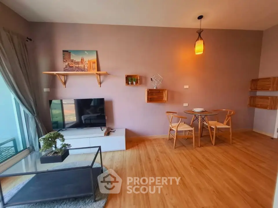 Modern living room with stylish decor and natural light, featuring a cozy dining area and entertainment setup.