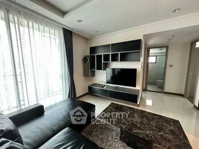 Modern living room with sleek black furniture and large TV, perfect for relaxation and entertainment.