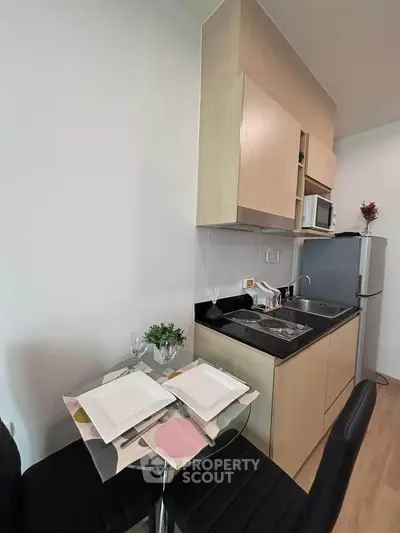 Modern compact kitchen with dining area, featuring sleek cabinetry and stainless steel appliances.