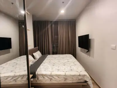 Modern bedroom with cozy bed, mirrored wardrobe, and wall-mounted TV in a stylish apartment.