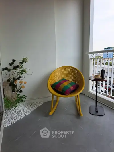 Chic balcony with modern yellow chair and colorful cushion, perfect for relaxation.