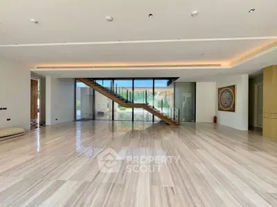 Spacious modern living room with elegant staircase and large windows