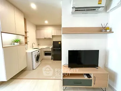 Modern open-layout kitchen and living room with washing machine and TV setup.