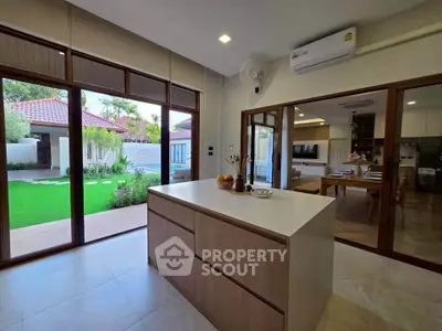 Modern kitchen with island and open view to lush garden and dining area