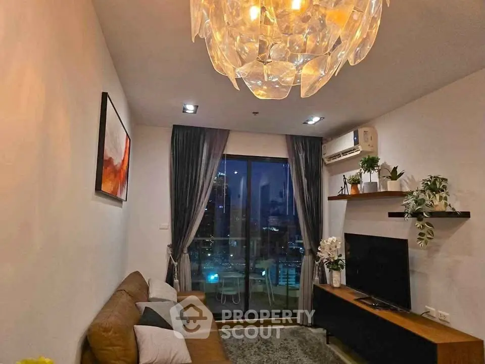 Modern living room with stylish chandelier and city view from balcony.