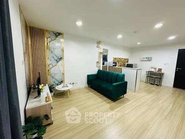 Modern living room with stylish decor and open layout, featuring a green sofa and sleek wooden flooring.