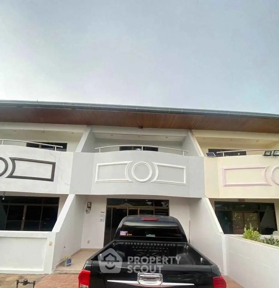 Modern townhouse exterior with parking space and sleek architectural design.