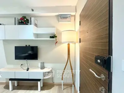 Modern living room with stylish decor and wooden door, featuring a sleek TV setup and elegant floor lamp.