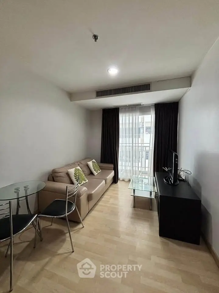 Modern living room with cozy sofa, glass dining table, and TV in a bright apartment.