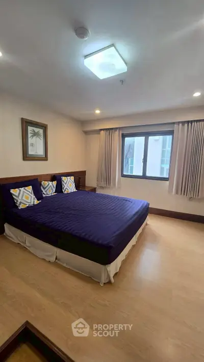 Spacious bedroom with modern decor and large window for natural light.