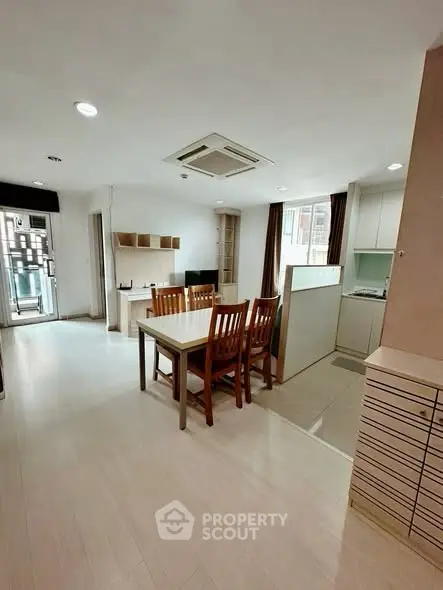 Spacious open-plan living and dining area with modern kitchen in a bright apartment.