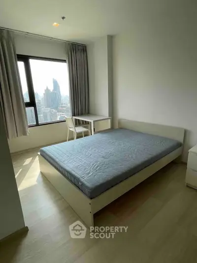 Modern bedroom with city view, featuring a bed and study desk, ideal for urban living.