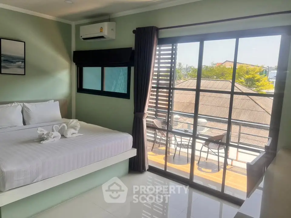 Bright bedroom with balcony view, modern decor, and air conditioning in a serene setting.