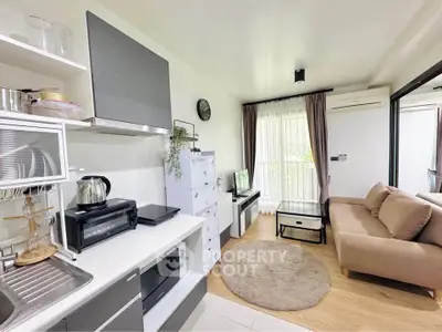Modern open-layout living room with kitchen, featuring cozy sofa and sleek appliances.