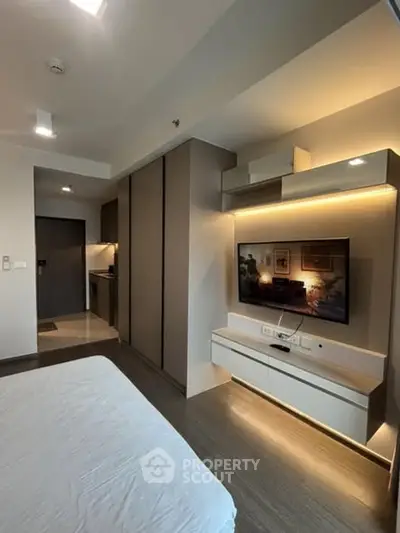 Modern bedroom with sleek design and integrated TV unit, featuring ambient lighting.