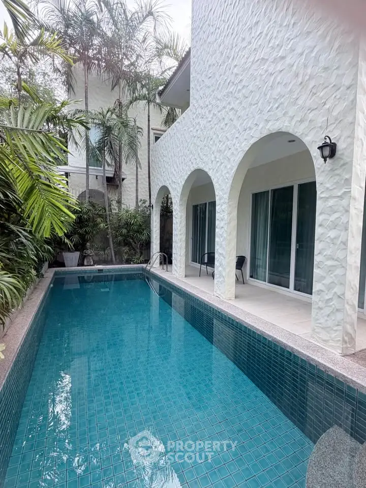 Luxurious villa with private pool and elegant arches surrounded by lush greenery.