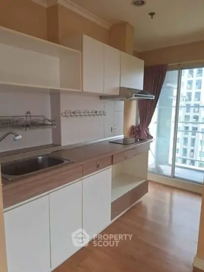 Modern kitchen with sleek cabinetry and balcony view in urban apartment