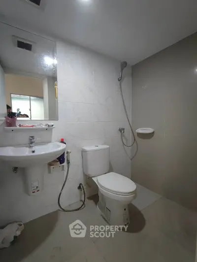 Modern bathroom with sleek fixtures and neutral tiles, featuring a shower and toilet.