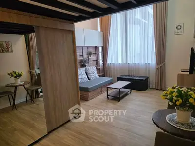 Stylish modern living room with wooden flooring, cozy seating, and large window for natural light.