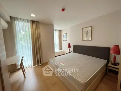 Spacious bedroom with large windows and modern furnishings in a stylish apartment.