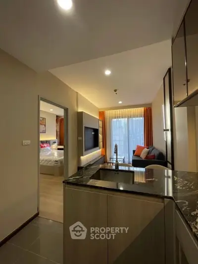 Modern open-layout apartment with stylish kitchen and cozy living area, featuring elegant lighting and contemporary decor.
