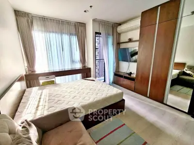 Modern bedroom with large window, stylish wardrobe, and cozy bed in a bright apartment.