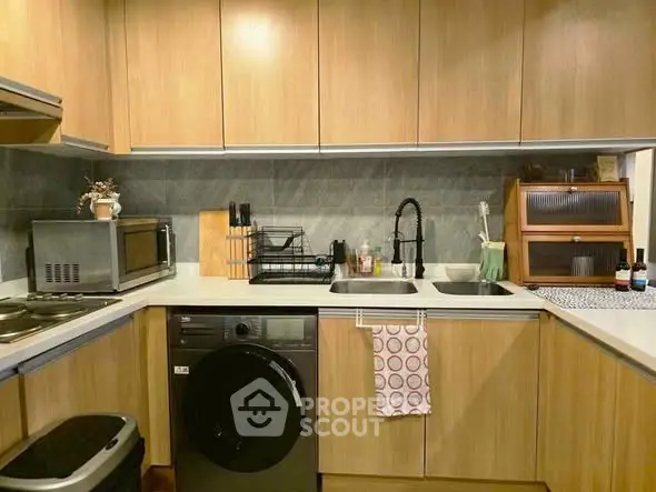 Modern kitchen with wooden cabinets, washing machine, and sleek appliances