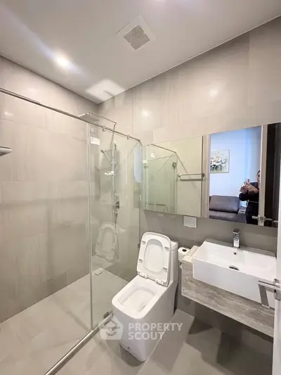 Modern bathroom with glass shower, sleek toilet, and stylish sink in a contemporary apartment.