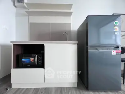 Modern kitchen with sleek cabinetry and stainless steel appliances, including a fridge and microwave.