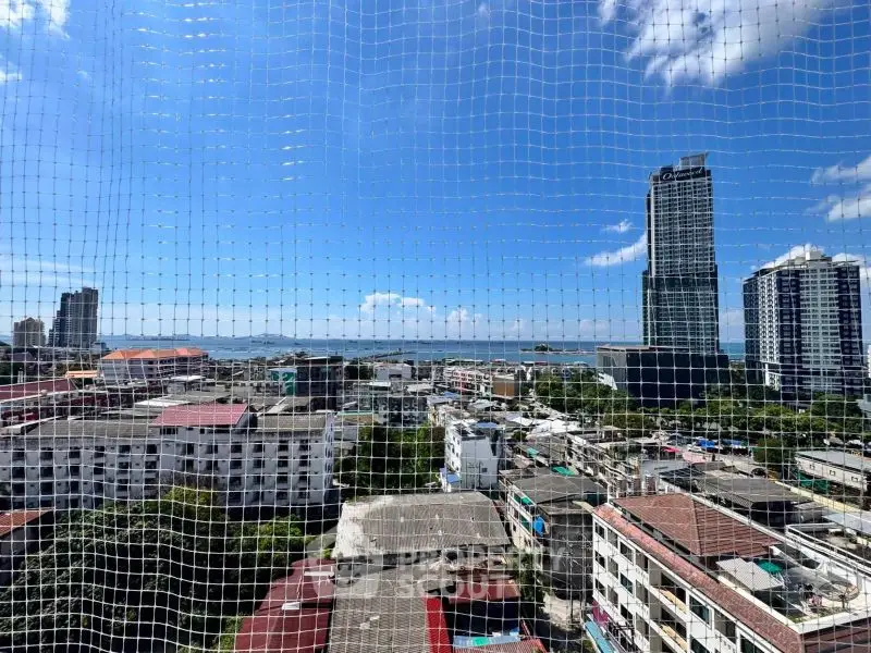 Stunning cityscape view from high-rise building showcasing urban skyline and ocean horizon.
