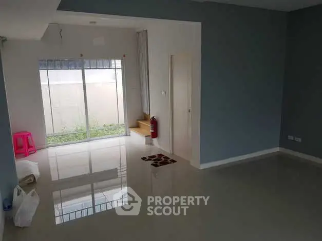 Spacious empty living room with glossy floor and large window for natural light.