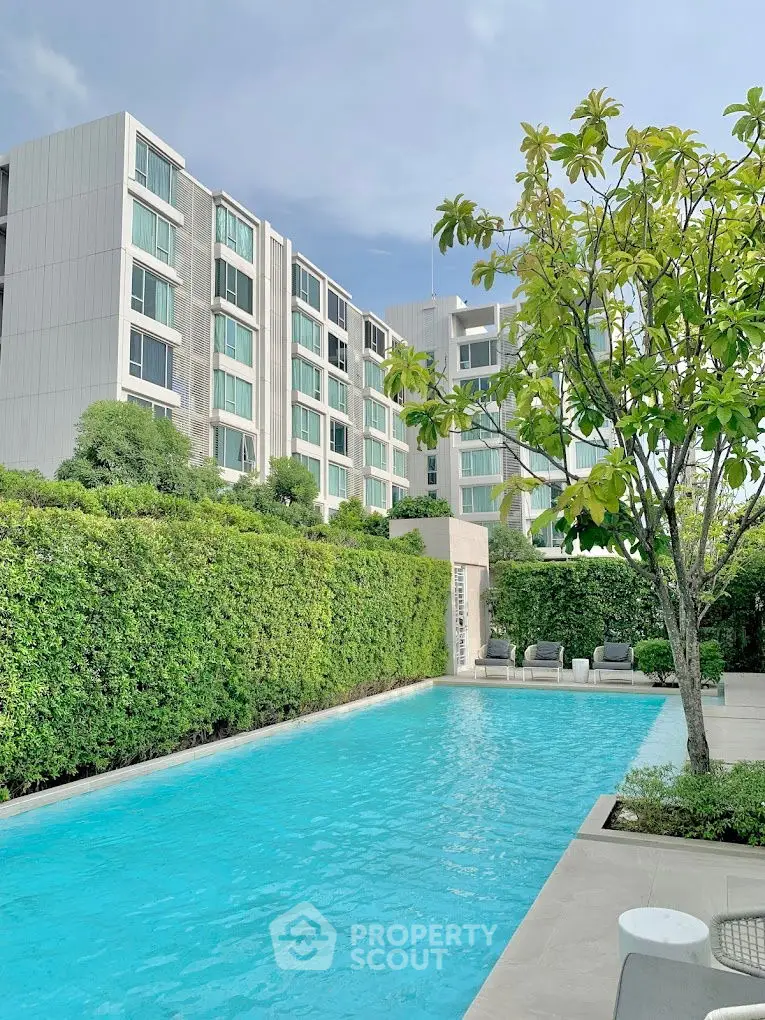Luxurious apartment complex with pristine swimming pool and lush greenery