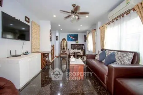 Spacious living room with modern decor, leather sofa, and large windows for natural light.